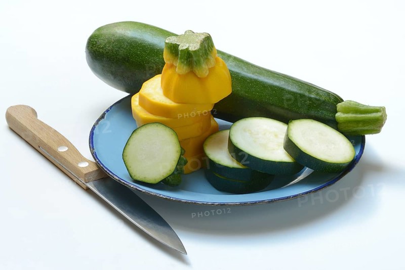 Green and yellow courgettes on a plate with a knife, Cucurbita pepo