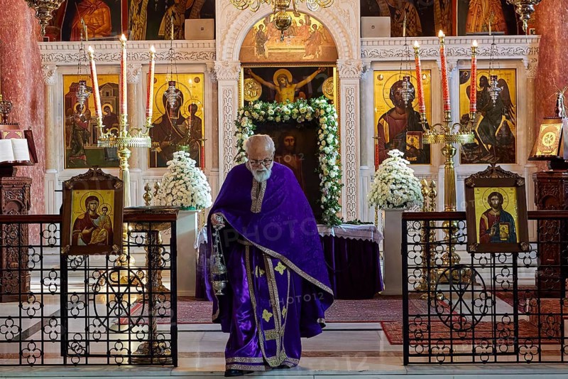 Priest in purple robe walking past an altar with icons and burning candles, Church of the Annunciation of the Blessed Virgin Mary, Rhodes Town, Greece, Orthodox Church, Dodecanese, Greek Islands, Rhodes Town, Holy Week, Rhodes