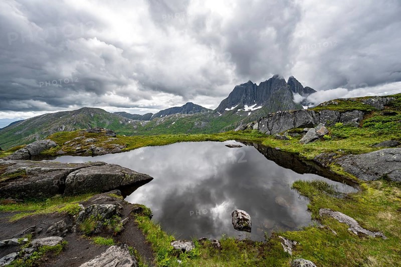 Small lake in mountain landscape, hike to Barden mountain, Breidtind mountain peak behind, Senja, Norway