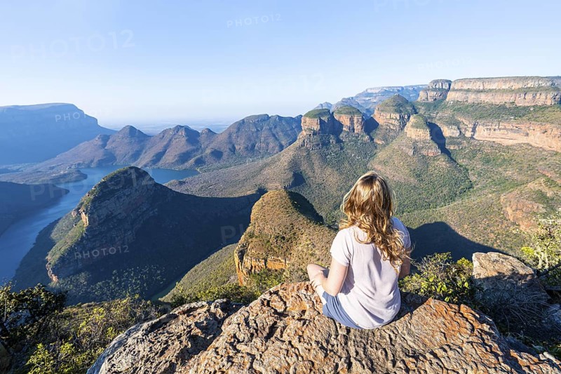 Hiker enjoying sunset at Blyde River Canyon with Three Rondawels peak, view of canyon with Blyde River and table mountains in the evening light, Canyon landscape, Panorama Route, Mpumalanga, South Africa