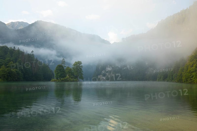 Mystical morning at Königssee in Schönau with boathouses and Christlieger. Sunrise and beautiful wafts of mist over the Königssee in the basin
