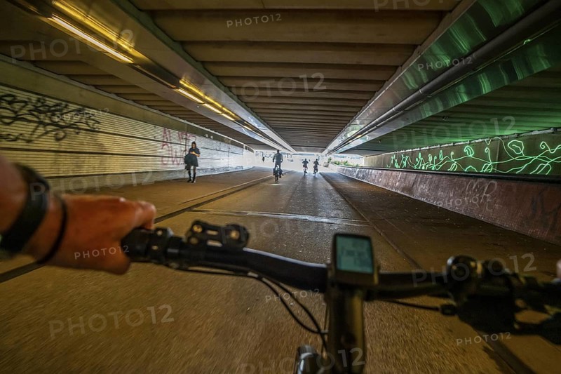 Ride your bike through the tunnel under the tracks of Utrecht Central, HBF, on the central cycle path on the Lange Viestraat, Vredenburg, in the city centre of Utrecht, lanes for pedestrians, cyclists and public transport vehicles are separated, dense cycle traffic, Netherlands