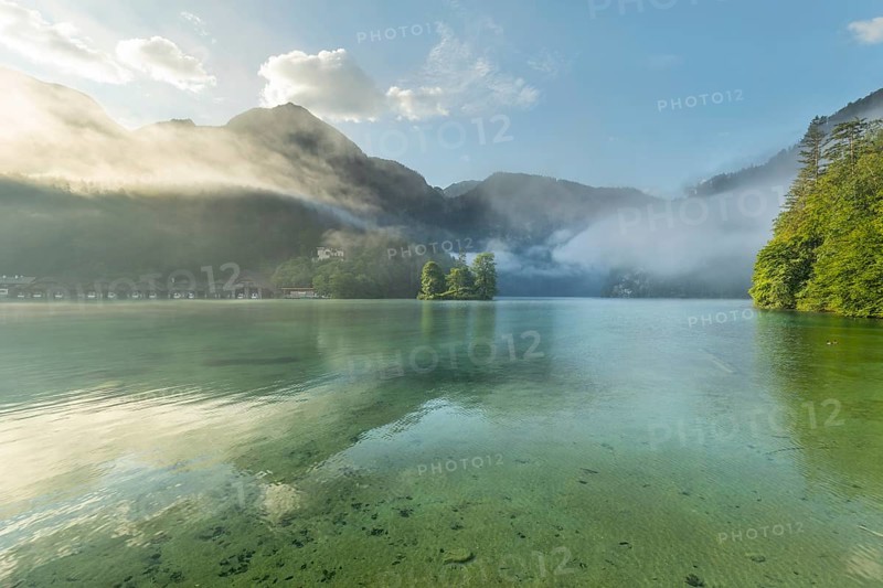 Mystical morning at Königssee in Schönau with boathouses and Christlieger. Sunrise and beautiful wafts of mist over the Königssee in the basin