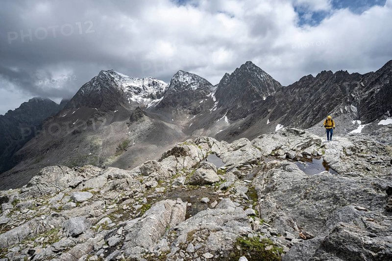 Mountaineer, Small mountain lakes in rocky mountain landscape, Niedere Gradenscharte, summit of Petzeck in the background, Schober group, Hohe Tauern National Park, Carinthia, Austria