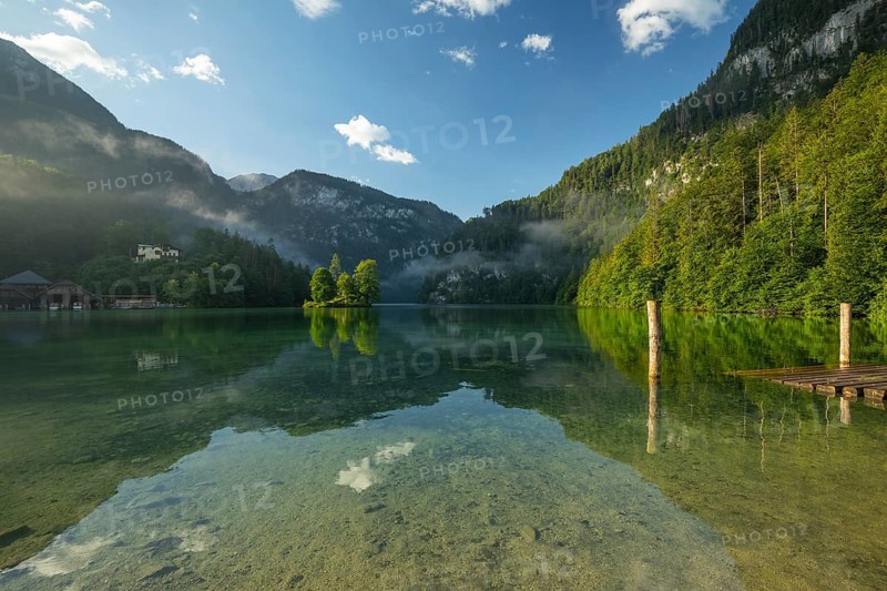 Mystical morning at Königssee in Schönau with boathouses and Christlieger. Sunrise and beautiful wafts of mist over the Königssee in the basin