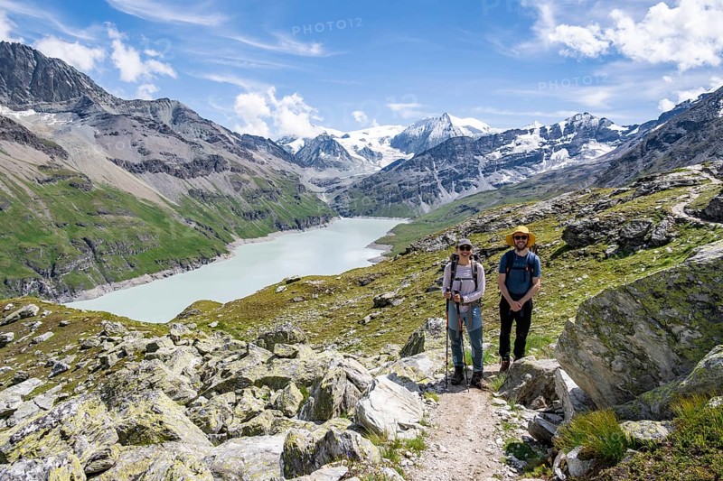 Mountaineer on a hiking trail at a blue mountain lake, reservoir Lac des Dix, behind mountain peak Mont Blanc de Cheilon, Hérménence, Valais Alps, Valais, Switzerland