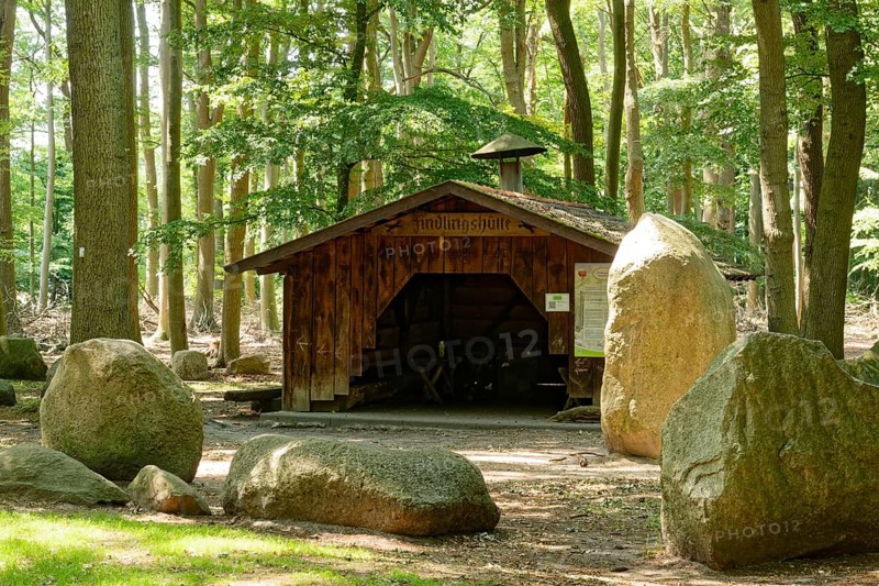 Erratic blocks and hut in the Neuenknick erratic block forest in the Teutoburg Forest. Around 2000 of the ice-age relics have been brought together in a collection. The erratic boulder forest includes a nature discovery trail and is equipped as a leisure and recreation centre. Petershagen, North Rhine-Westphalia. Germany