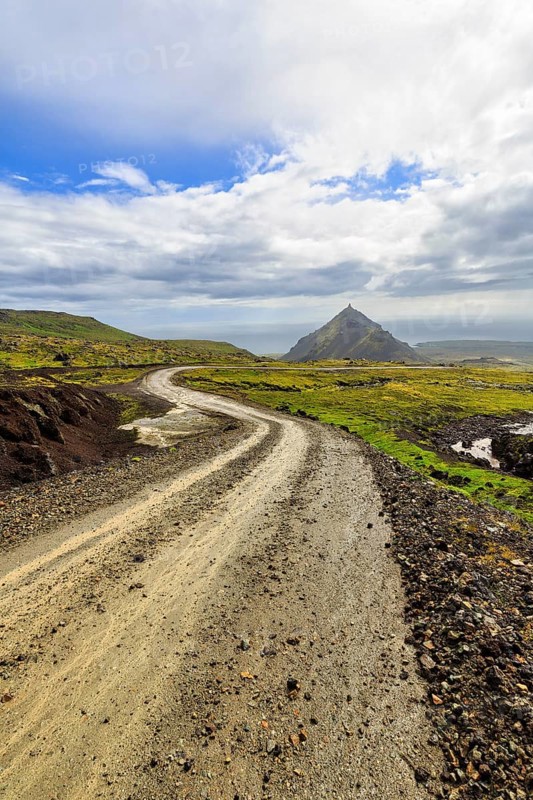 Gravel track through barren moss-covered volcanic landscape, cone-shaped mountain Stapafell, rain clouds, changeable weather, Arnarstapi, Snaefellsjökull volcanic system, Snaefellsnes peninsula, West Iceland, Iceland
