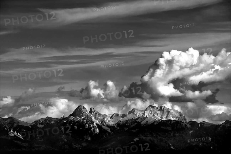 Clouds drift over the striking peaks of the Swiss mountains, showcasing a breathtaking view near Lake Geneva. The landscape highlights nature's beauty and tranquility. Switzerland