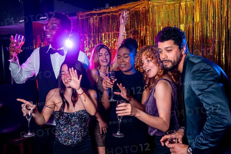 Group of cheerful elegant friends having fun together and drinking sparkling wine while dancing and celebrating at nightclub