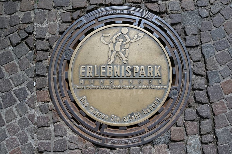 Municipal manhole cover with an advert for an adventure park, Biberach an der Riß, Baden-Württemberg, Germany