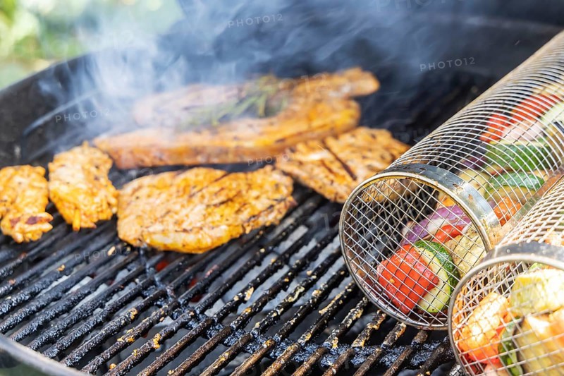 Barbecue in the garden. Meat and vegetables, vegetarian and vegan, are served on the kettle grill. Barbecue baskets for gently braising carrots, courgettes or peppers are right on trend. Münsingen, Baden-Württemberg, Germany