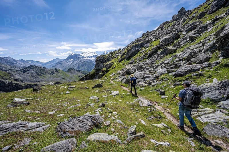 Mountaineer on hiking trail in mountain landscape, descent at Col du Louvie, view of the summit of the Grand Combine, Valais Alps, Val de Bagnes, Valais, Switzerland