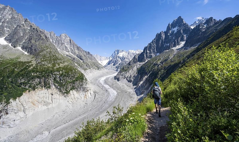 Picturesque mountain landscape with imposing mountain peaks and glaciers, mountaineer on hiking trail, Grand Balcon Nord, glacier tongue Mer de Glace, behind Grandes Jorasses, Mont Blanc massif, Montenvers, Chamonix, Haute-Savoie, France