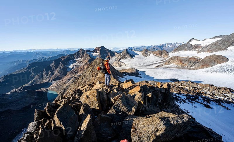 Mountaineer on a rocky ridge, ascent to the Wilder Freiger, behind the summit of the Becher with Becherhaus, picturesque high mountain landscape, view of the Übeltalferner glacier and rocky mountain peaks, Stubai Alps, South Tyrol, Italy