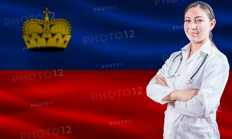 Female doctor on Liechtenstein flag. Doctor with crossed arms on Liechtenstein flag. Liechtenstein health and care concept