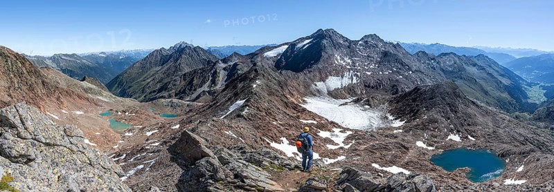 Mountain panorama, mountaineer in rocky high mountain landscape at the Rotgratscharte, view of mountain landscape with blue glacier lake, descent from the summit Roter Grat, Stubai Alps, South Tyrol, Italy