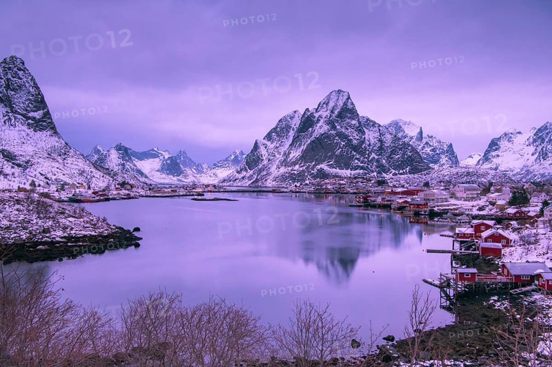Fishermen's Village in front of snowy mountain range at the coastline in winter, Lofoten, Norway