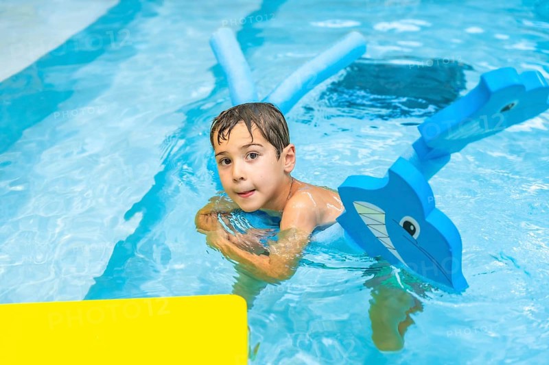 Happy boy playing with inflatable toy whale in swimming pool during summer vacation, enjoying refreshing water and having fun on sunny day