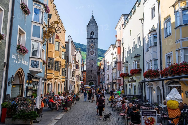 Old town, colourful houses in the main street, Zwölferturm tower at the back, old town, Sterzing, South Tyrol, Italy
