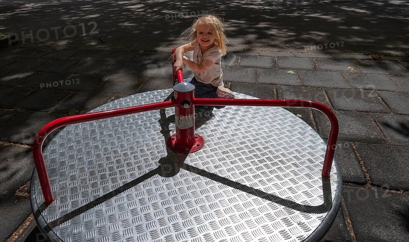 Outdoor shot, little girl, 3 years old, blonde, playing on a merry-go-round, children's playground, playground, Stuttgart, Baden-Württemberg, Germany