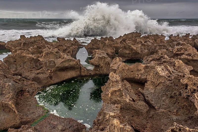 A rocky area with a hole in the ground. The hole is filled with water. The water is brown in colour. Rabat, Morocco