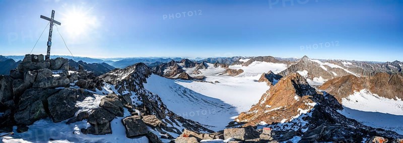 Mountain panorama at the Wilder Freiger summit with summit cross, picturesque high mountain landscape with snow, view of the Übeltalferner glacier and rocky mountain peaks Königshofspitz and Sonklarspitze, Wilder Pfaff and Ruderhofspitze, Stubai Alps, South Tyrol, Italy