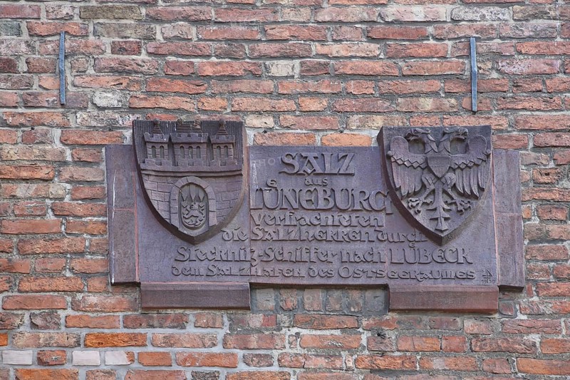 City coat of arms with inscription on the history of the city on the historical trade in salt, by ship via Stecknitz to Lüneburg, double eagle, production, sale, monochrome, brick wall, salt warehouse, old town, Lübeck, Schleswig-Holstein, Germany