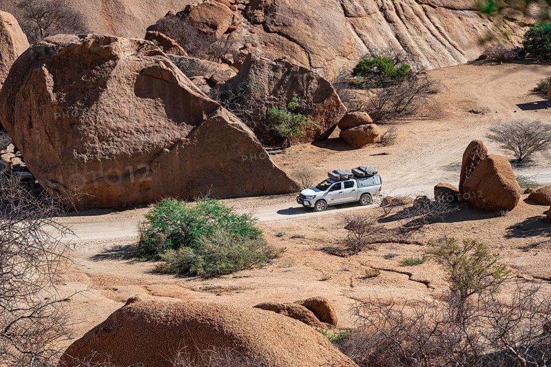 Off-road car between rocks, Pontok Mountains, Great Spitzkoppe, Spitzkoppe, Great Spitzkoppe Nature Reserve, Namibia