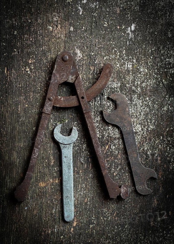 A collection of vintage tools, including a caliper and several wrenches, rests on a rustic wooden surface, highlighting their age and functional design attractive to enthusiasts and craftsmen alike