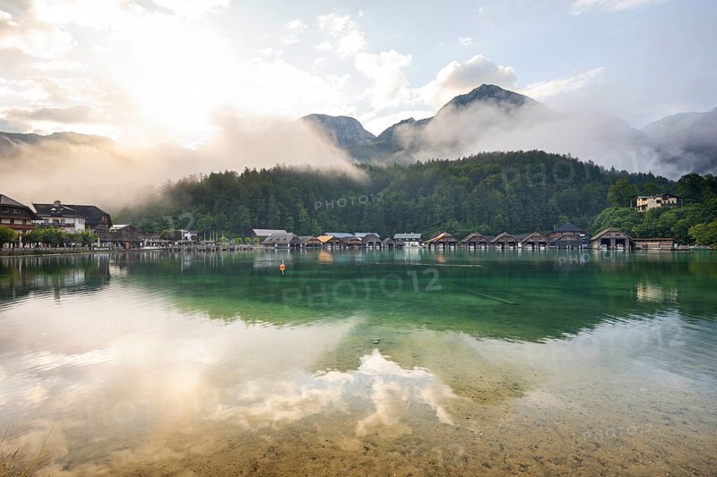 Mystical morning at Königssee in Schönau with boathouses. Sunrise and beautiful wafts of mist over the Königssee in the basin