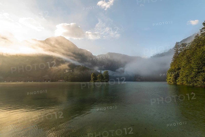 Mystical morning at Königssee in Schönau with boathouses and Christlieger. Sunrise and beautiful wafts of mist over the Königssee in the basin