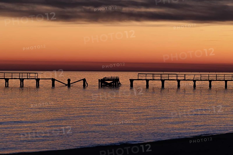 Sunset behind dilapidated fishing pier damaged by hurricanes on the Mississippi Gulf Coast in Long Beach, Mississippi