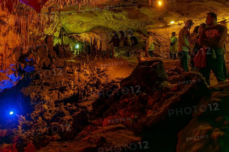 Tourists walking past limestone rock formations in a cave at Florida Caverns State Park in the Florida panhandle near Marianna