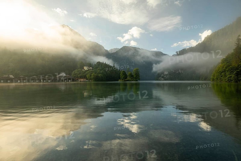 Mystical morning at Königssee in Schönau with boathouses and Christlieger. Sunrise and beautiful wafts of mist over the Königssee in the basin