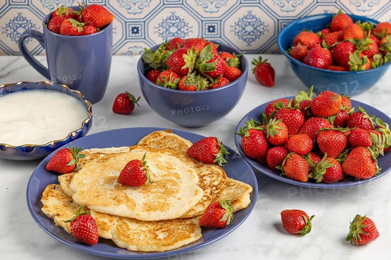 Pancakes with strawberries and yoghurt on blue crockery