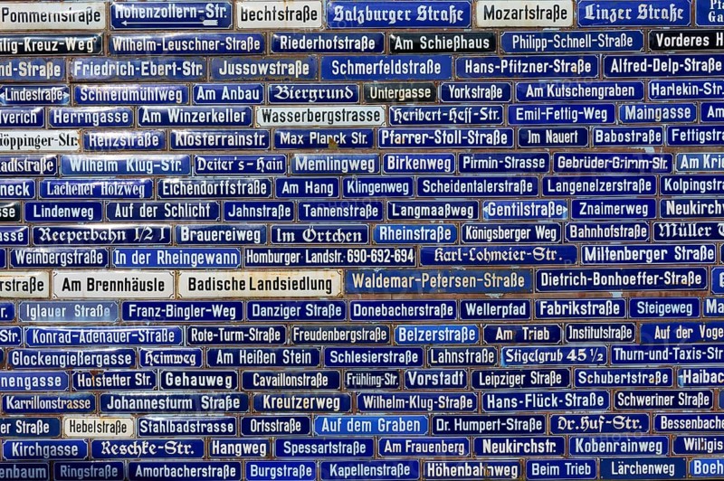 Wall with many blue street signs showing different names, Amorbach, Odenwald, Bavaria, Germany