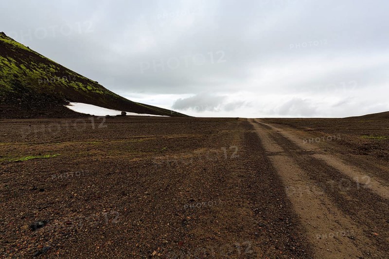 Gravel track, barren volcanic landscape with snowfields, mountain peaks with rain clouds, Snaefellsjökull, Snæfellsnes peninsula, Snaefellsnes, West Iceland, Iceland