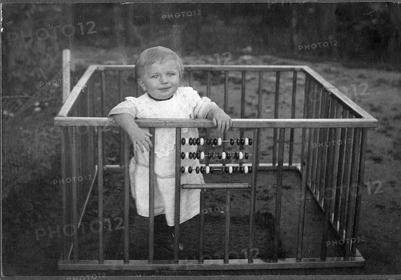 Child in a playpen, 1920s, A smiling child stands in a grid with an abacus in a nostalgic, historical setting, Historical photo