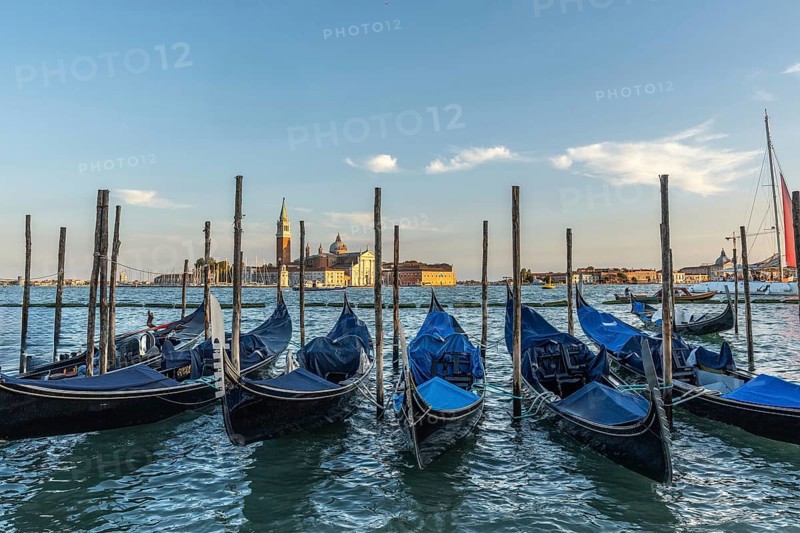 Gondolas moored at sunset with the island of san giorgio maggiore in the background, creating a picturesque venetian scene