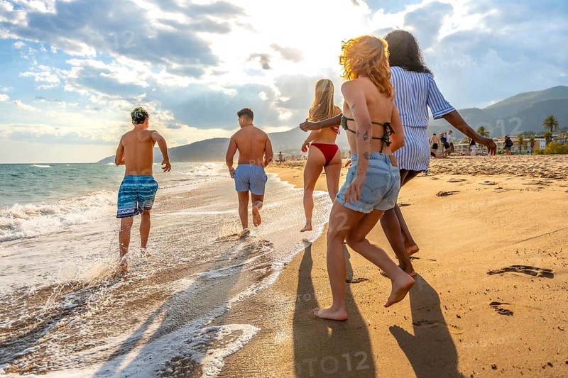 Friends running along the beach, soaking up the sun and enjoying a carefree summer vacation filled with laughter and joy