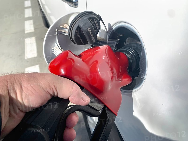 Male hand holding gas pump nossle pumping gas into vehicle