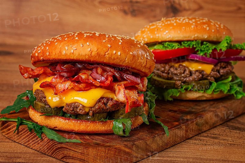Two burgers with beef patty, fried bacon, cheddar cheese, tomatoes, homemade, no people