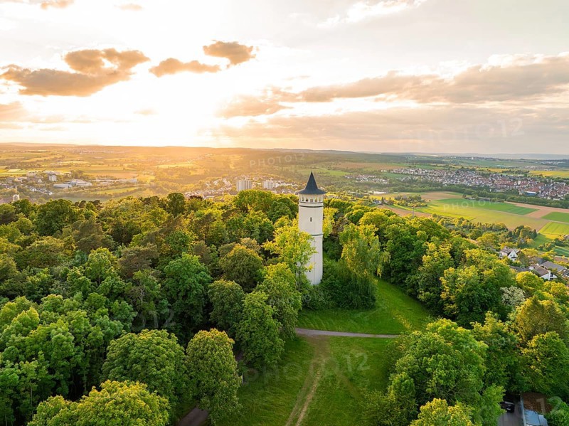Tower with surrounding paths rises out of a green thicket under the sun, Engelberg Tower, Leonberg, Germany