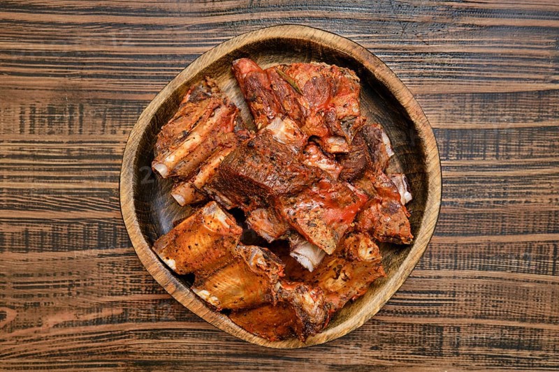 Tender short beef ribs are perfectly roasted in the oven, showcasing a rich, savory flavor. The ribs are served on a rustic wooden plate, inviting you to enjoy a delicious meal