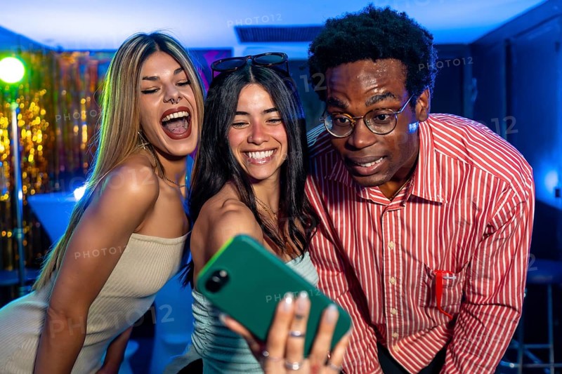 Cheerful multi ethnic friends gathering together, capturing a fun selfie at a vibrant party, enjoying the lively music and nightlife atmosphere