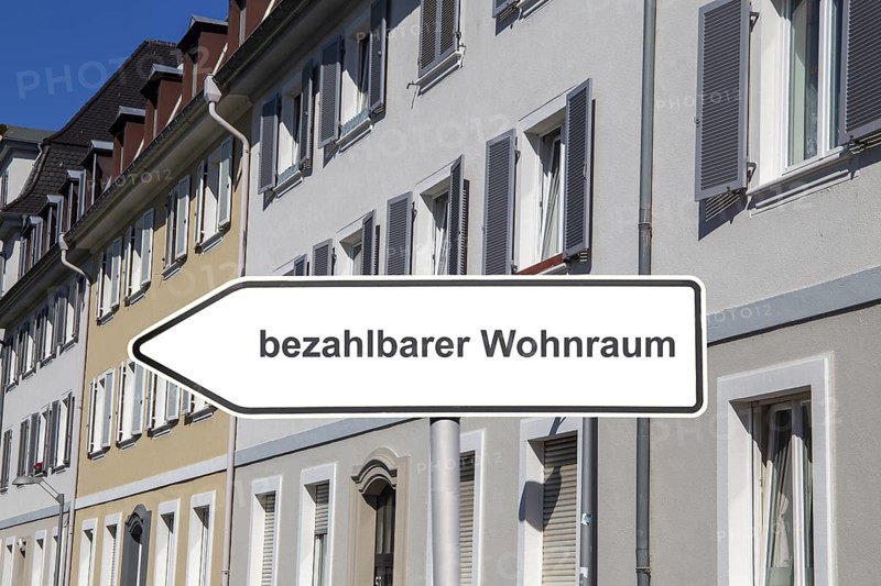 (Photomontage) Sign with the inscription BEZAHLBARER WOHNRAUM in front of municipal apartment blocks