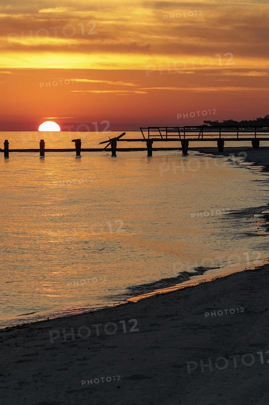 Sunset behind dilapidated fishing pier damaged by hurricanes on the Mississippi Gulf Coast in Long Beach, Mississippi