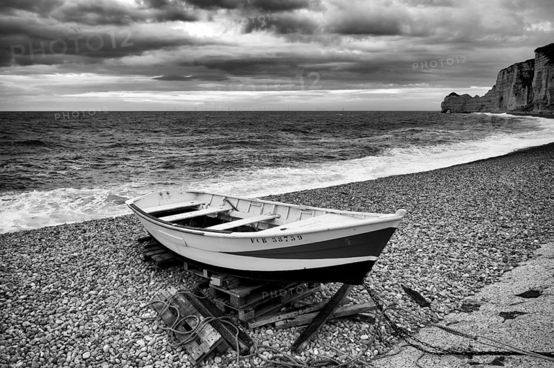 Boat, rowing boat, lies on the beach, pebble beach, rock arch Falaise or Porte d'Amont, Étretat, sea, clouds, steep coast, cliffs, chalk cliffs, alabaster coast, La Côte d'Albâtre, black and white, Normandy, Seine-Maritime, France
