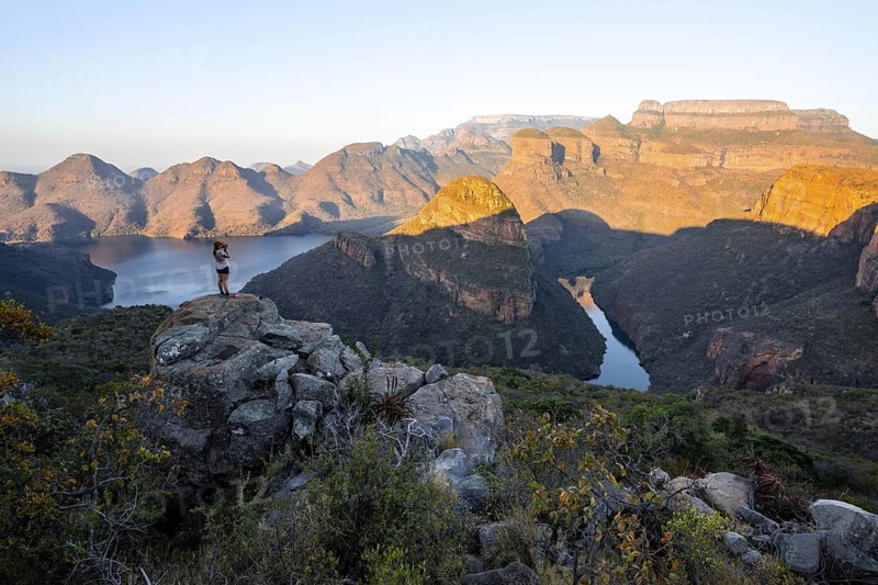 Hiker enjoying sunset at Blyde River Canyon with Three Rondawels peak, view of canyon with Blyde River and table mountains in the evening light, Canyon landscape, Panorama Route, Mpumalanga, South Africa